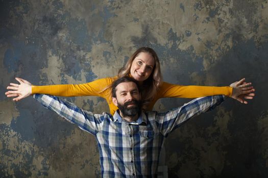 Love and relationship concept. Happy adult couple hugging, smiling wide and looking at camera, standing together on blue abstract background