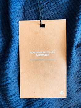 Contains recycled polyester fashion label tag, sale price card on luxury fabric background, shopping and retail concept