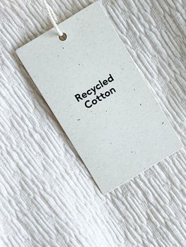 Recycled cotton fashion label tag, sale price card on luxury fabric background, shopping and retail concept