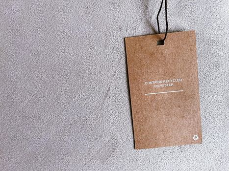 Contains recycled polyester fashion label tag, sale price card on luxury fabric background, shopping and retail concept