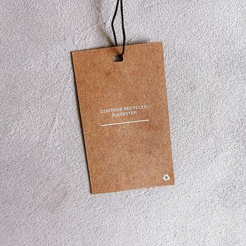 Contains recycled polyester fashion label tag, sale price card on luxury fabric background, shopping and retail concept