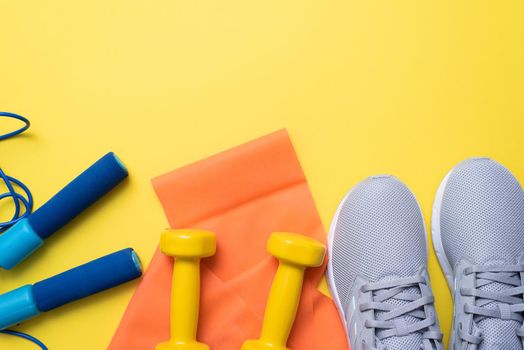 Flat lay of fitness equipment on yellow background. Top view of home workout equipment. Fitness objects on yellow background with copy space.