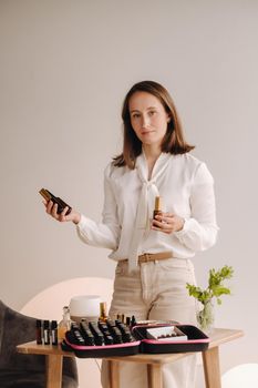 A girl with a white blouse holds bottles of essential oils in her hands.