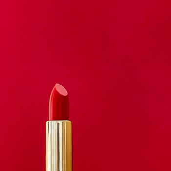Red lipstick in golden tube on colour background, luxury make-up and cosmetics for beauty brand product design concept