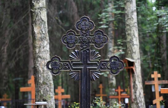 Black metal cross closeup on background with orthodox cemetery