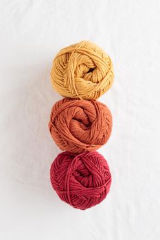 Needlework. Balls of cotton yarn warm colors on a white table, copy space
