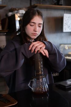 pretty brunette girl making aeropress coffee in modern coffee shop.