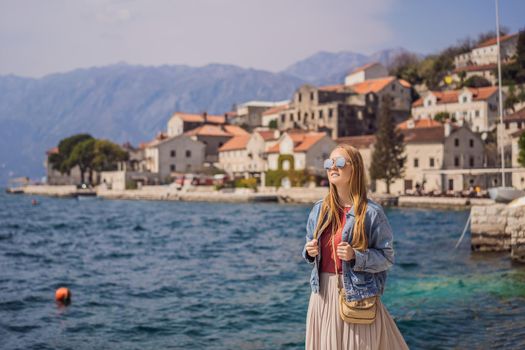 Woman tourist enjoying Colorful street in Old town of Perast on a sunny day, Montenegro. Travel to Montenegro concept. Scenic panorama view of the historic town of Perast at famous Bay of Kotor on a beautiful sunny day with blue sky and clouds in summer, Montenegro, southern Europe.