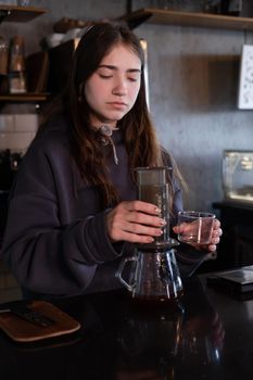 pretty brunette girl making aeropress coffee in modern coffee shop.