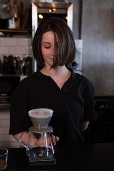 charming brunette woman barista making filter coffee in coffee shop. brewing coffee in cafe.