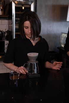 charming brunette woman barista making filter coffee in coffee shop. brewing coffee in cafe.