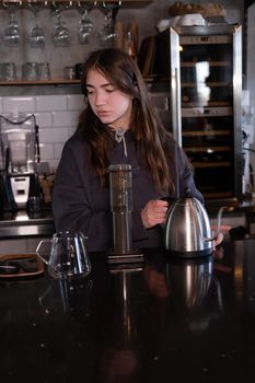 pretty brunette girl making aeropress coffee in modern coffee shop.