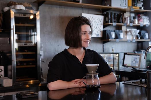 charming brunette woman barista making filter coffee in coffee shop. brewing coffee in cafe.