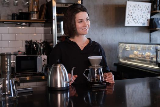 charming brunette woman barista making filter coffee in coffee shop. brewing coffee in cafe.