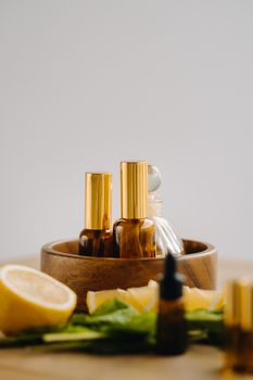 Essential oil in bottles with lemon and mint fragrance lying on a wooden surface.