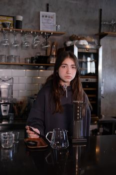 pretty brunette girl making aeropress coffee in modern coffee shop.