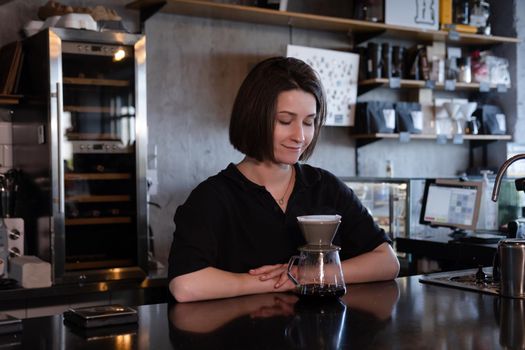 charming brunette woman barista making filter coffee in coffee shop. brewing coffee in cafe.