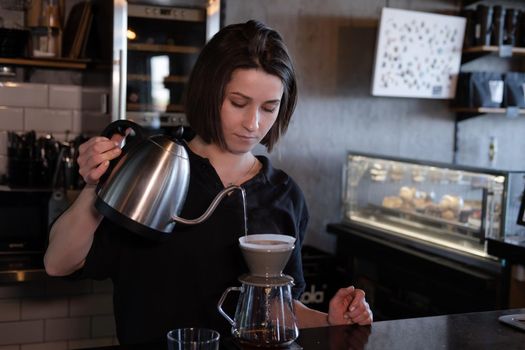 charming brunette woman barista making filter coffee in coffee shop. brewing coffee in cafe.