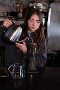 pretty brunette girl making aeropress coffee in modern coffee shop.