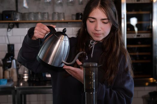 pretty brunette girl making aeropress coffee in modern coffee shop.