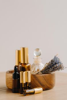 Essential oil in bottles with lavender fragrance, lying on a wooden surface.