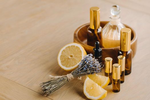 Essential oil in bottles with lemon and lavender fragrance, lying on a wooden surface.