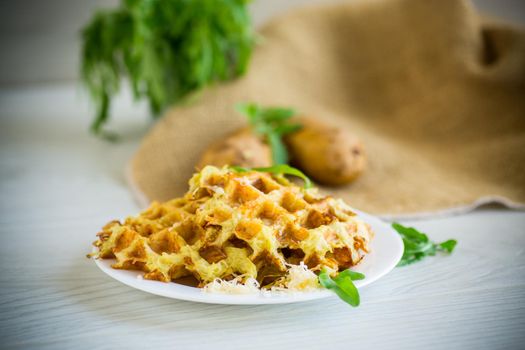 fried potato waffles with cheese in a plate on a light wooden table.