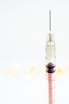 Syringe, injection needle and some pill on white background