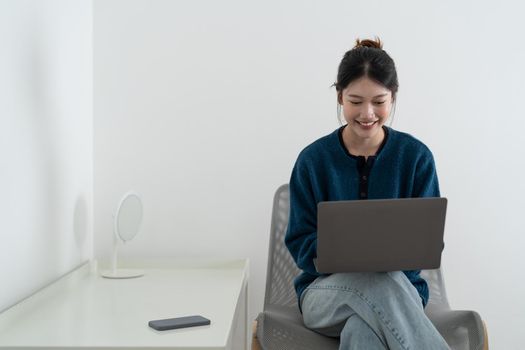 Happy smiling woman sitting on sofa, couch and using laptop at living room at home, watching funny video, learning language, video calling, mother working online.