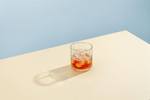 Glass with Whiskey and Ice Cube on Table on Blue Background. Modern Isometric Style. Creative Concept.