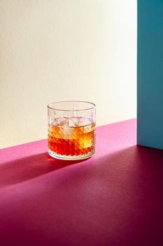 Glass with Whiskey and Ice Cube on Table with Hard Shadows. Modern Isometric Style. Creative Concept.