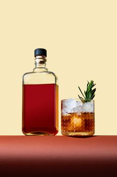 Bottle and Glass with Whiskey and Ice on Brown Table on Light Background. Modern Style. Creative Concept.