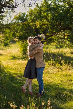 young couple hugging in nature, girl holding flowers