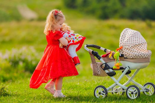 a girl rolls her doll on a toy stroller