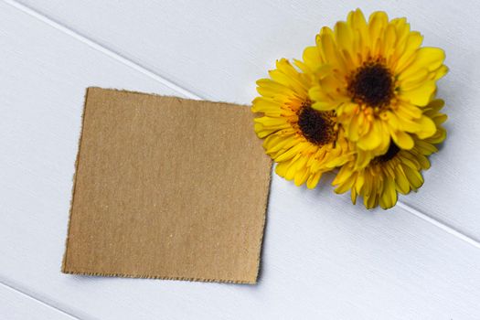 Torn brown paper on wooden surface and sunflower flat lay with copy space. Directly above.
