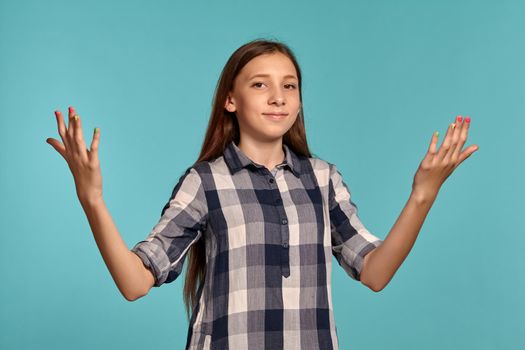 Portrait of a beautiful teenage lady in a casual checkered shirt posing against a blue studio background. Long hair, healthy clean skin and brown eyes. Sincere emotions concept. Copy space.