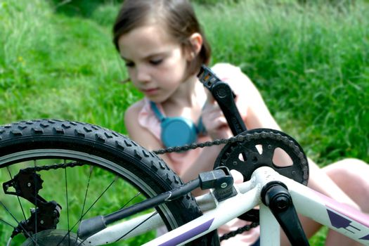 a child girl has damaged a bicycle wheel and is making repairs photo without processing. High quality photo