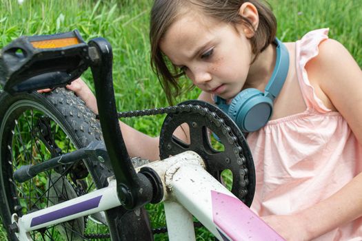 a child girl has damaged a bicycle wheel and is making repairs photo without processing. High quality photo