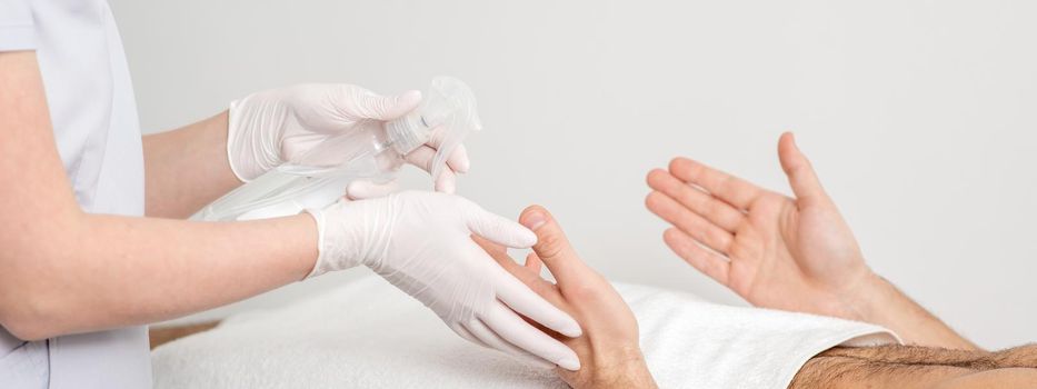 Nurse hand sanitizing hands of male patient in the hospital. Coronavirus protection concept.