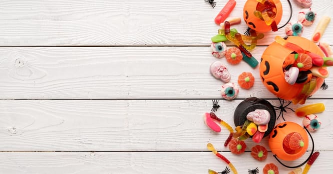 Halloween concept. Colorful sweets for Halloween party on white wooden background, top view flat lay