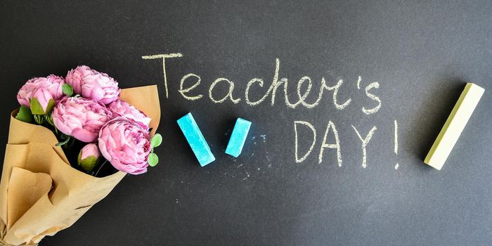 Flat lay composition with flowers peonies bouquet and inscription TEACHER'S DAY on black chalkboard. Back to school. School holidays