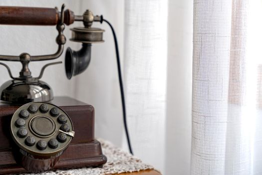 Old black phone on a wooden table. Copy space for your text . High quality photo