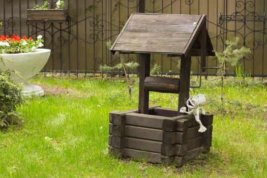 Wooden well to a picturesque place on green grass.