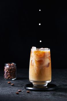 Cold Summer Drink. Iced Coffee with Milk Drops in Tall Glass on Dark Background. Drinks in Motion.