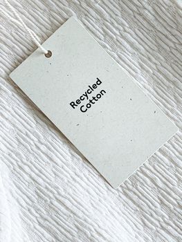 Recycled cotton fashion label tag, sale price card on luxury fabric background, shopping and retail concept