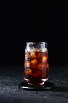 Iced Cola or Cold Coffee in Tall Glass on Dark Background. Concept Refreshing Summer Drink.