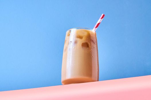 Iced Coffee with Milk in Tall Glasses on Pink Table and Blue Background. Trendy Hero View. Horizontal Orientation.