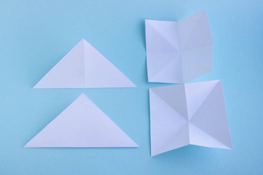 Handmade white trendy geometric polygonal paper origami fish on blue background.Step 1. Horizontal poster.