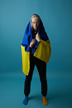 A real Ukrainian blonde woman during the war with the state yellow and blue Ukrainian flag on her head. Russia attacked Ukraine on February 24, 2022.