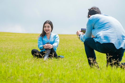 A guy taking a picture of a girl in the field, Boyfriend taking a picture of his girlfriend in the field, Two friends taking photos with the cell phone in the field